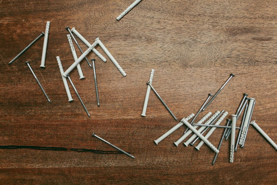 Close-up of nylon anchors and screws scattered on a wooden surface, perfect for DIY projects.