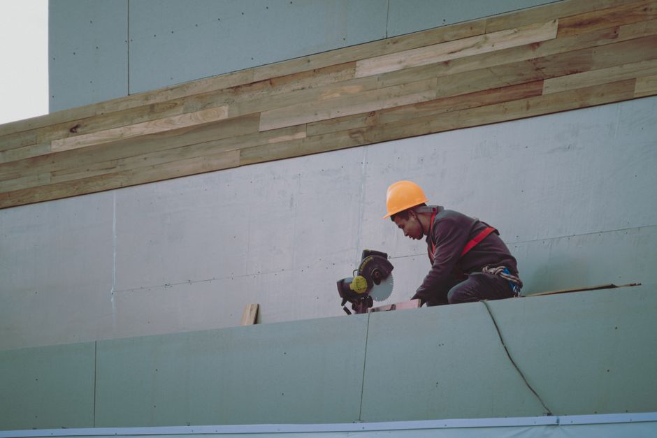 Construction worker with hard hat operating a circular saw on a building site.